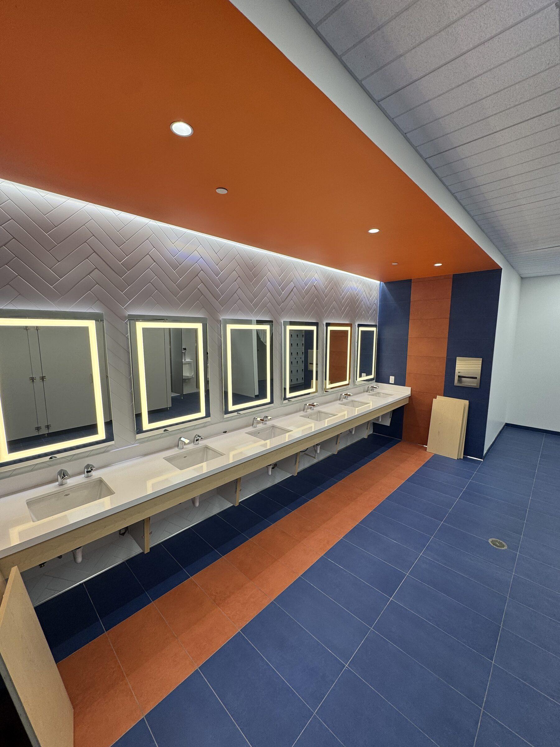 Locker-room vanity with backlit mirrors and herringbone tile, gleaming after a detail clean