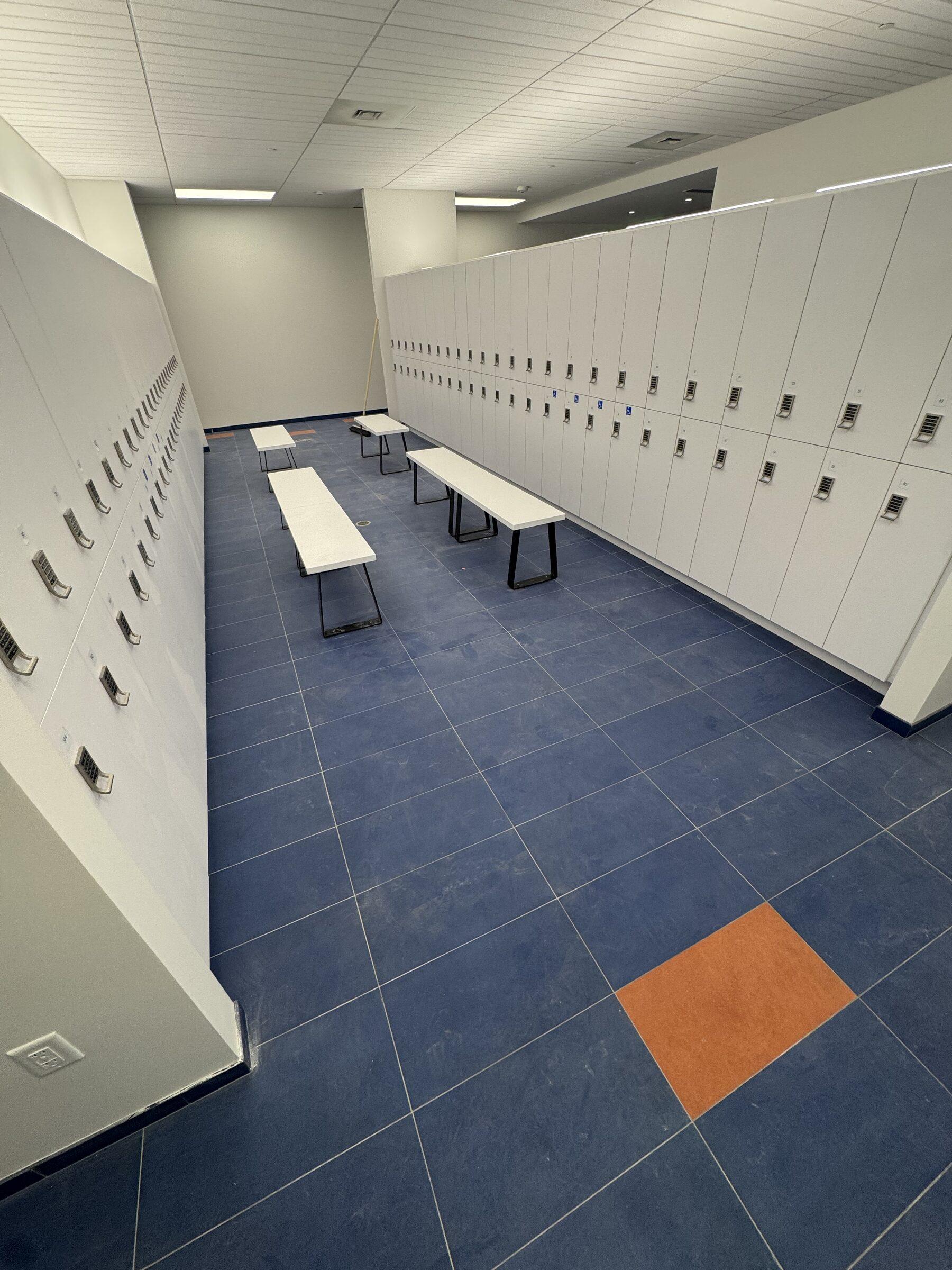 White locker wall and benches with a freshly cleaned tile floor