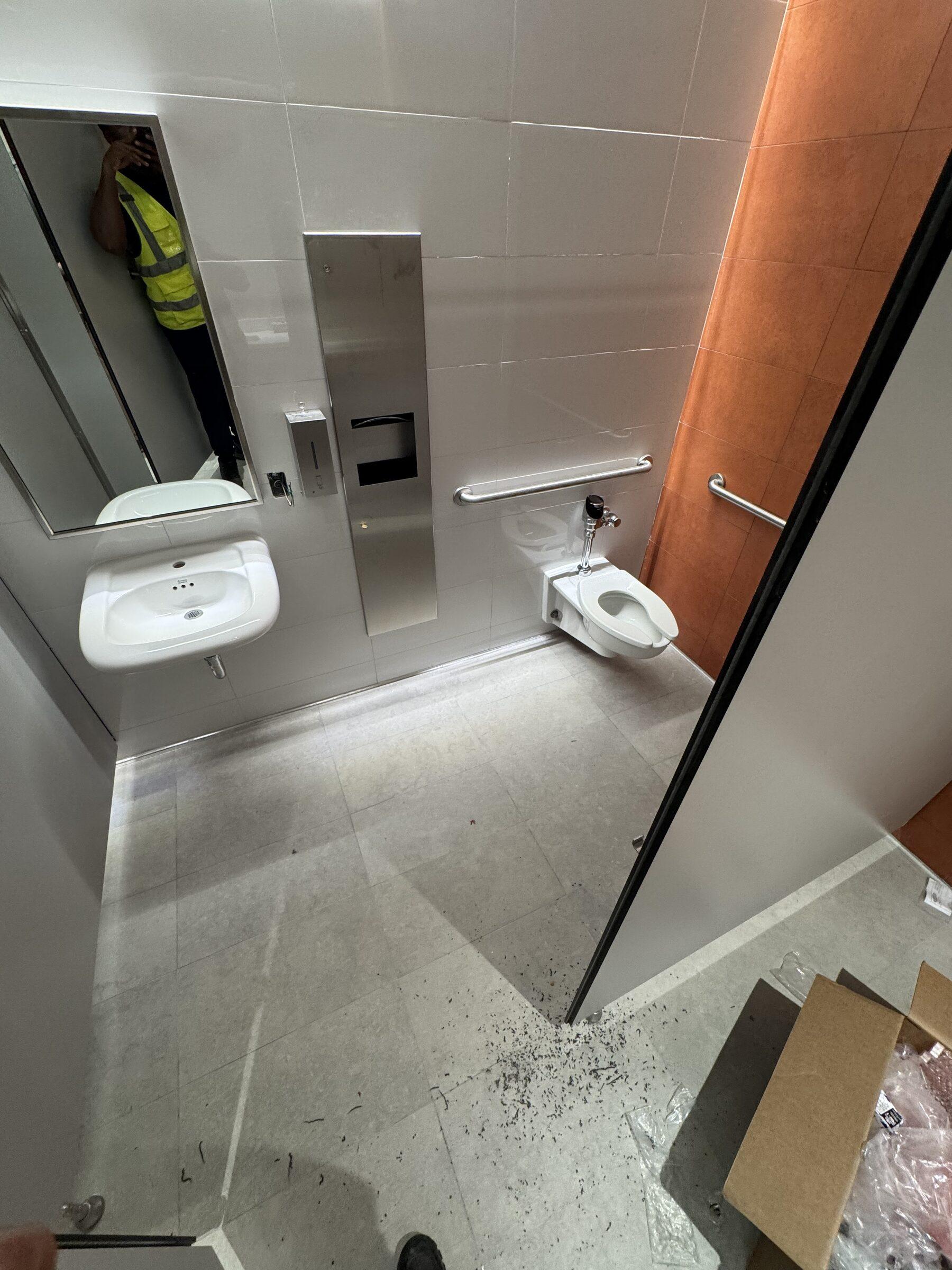 Restroom stall area mid-build with dust and debris, pre-clean