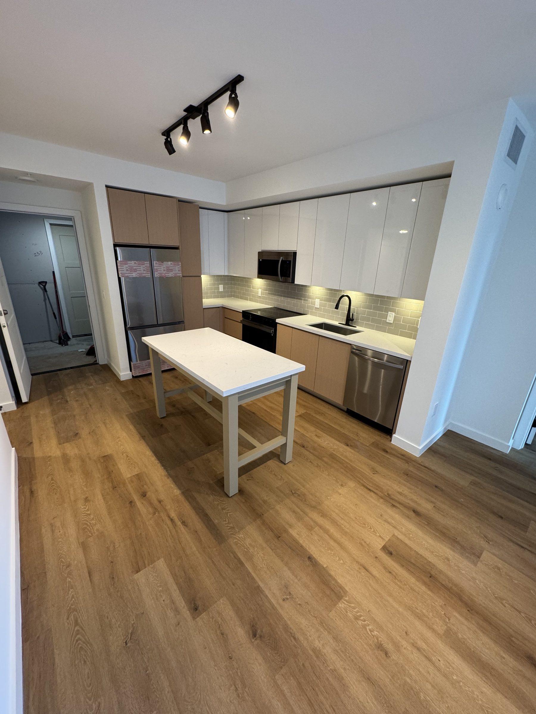 Apartment kitchen move-in ready after a post-construction clean — oak floors, white cabinetry