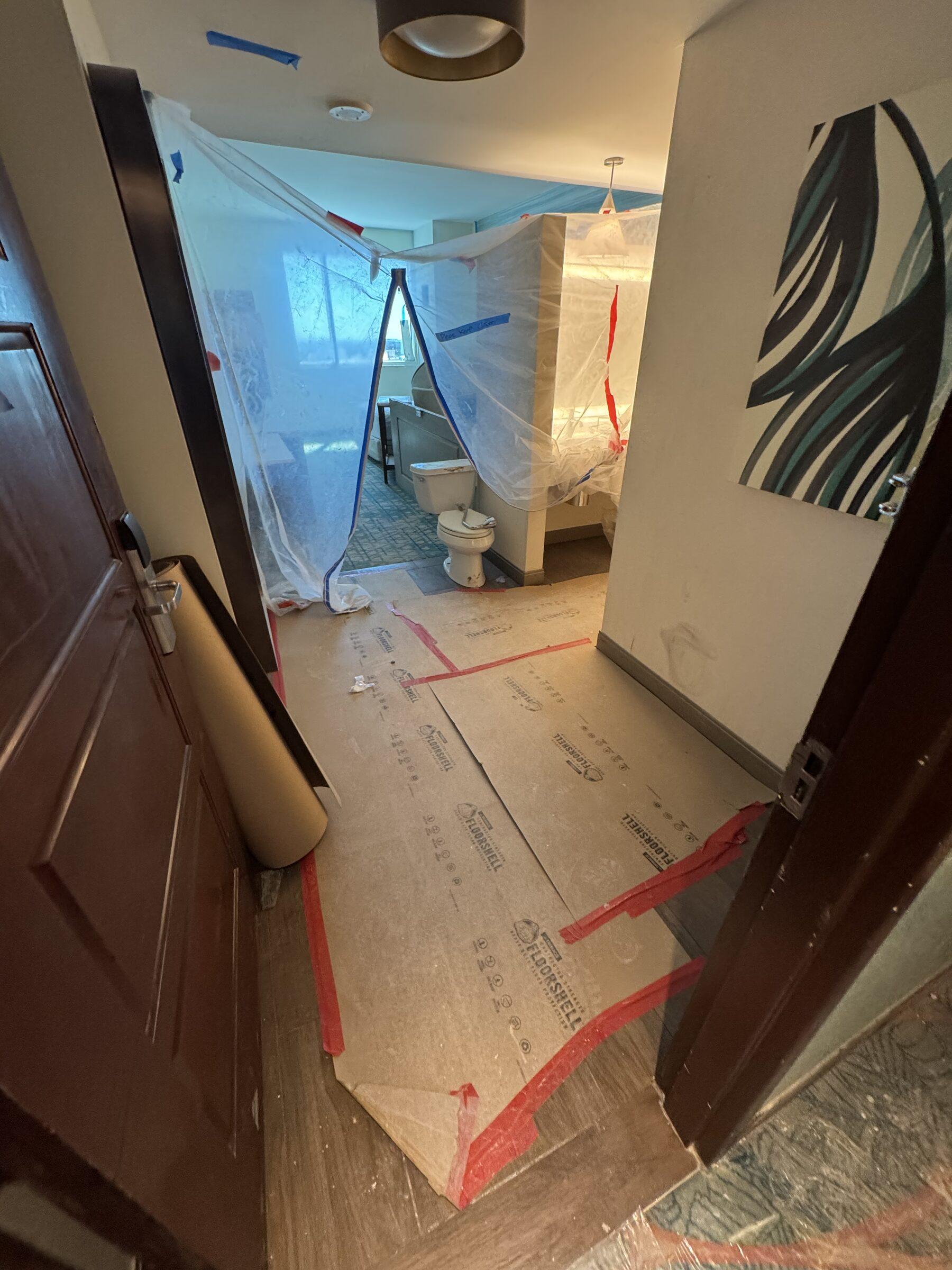 Bathroom mid-renovation with dust containment and floor protection, ready for a rough clean