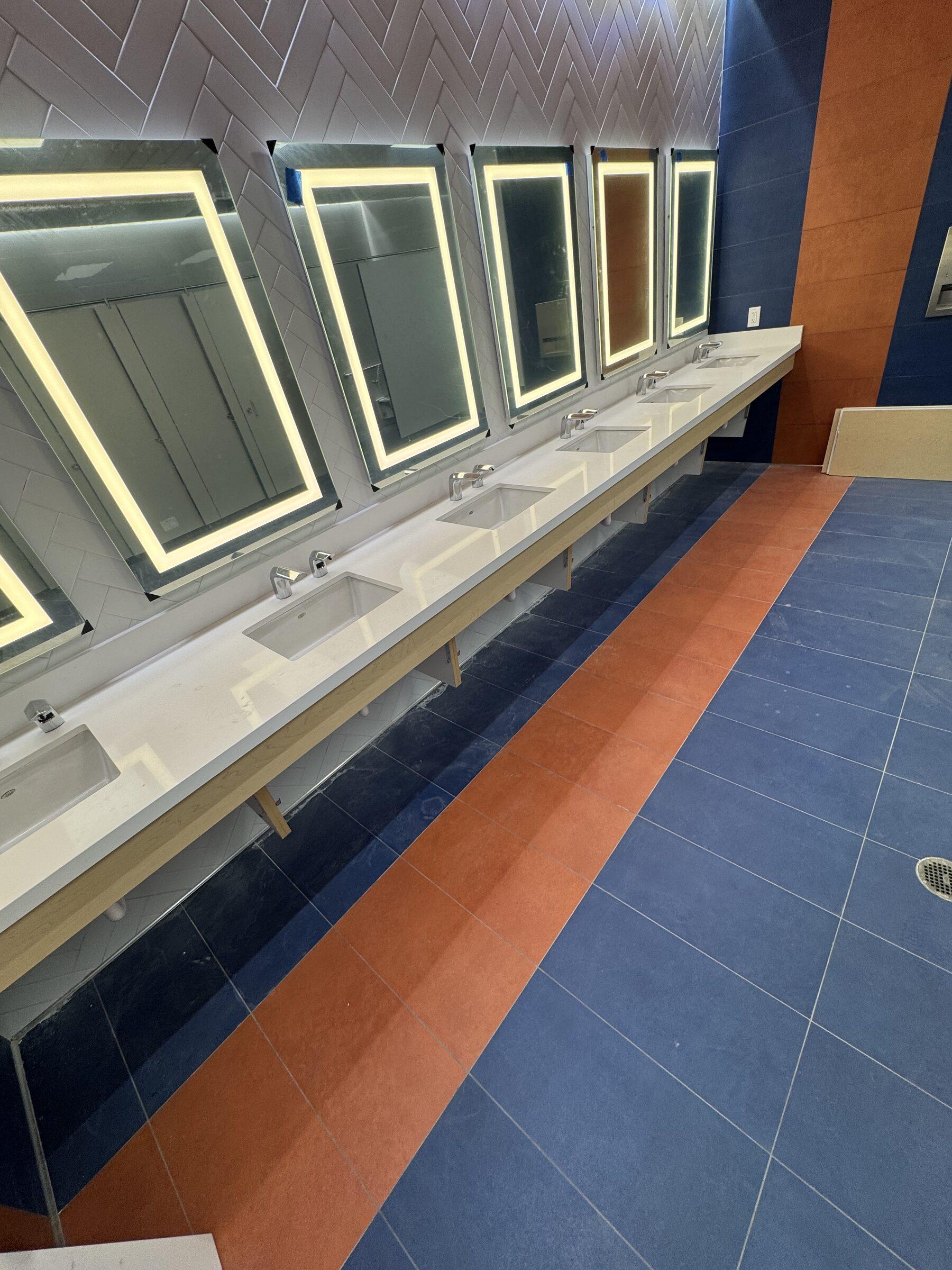Row of backlit vanity mirrors in a locker room we service